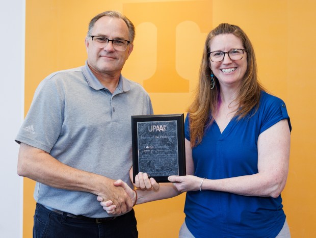 Moraine Valley Community College visual media coordinator Glenn Carpenter, left, receives the Master of the Profession Award from the University Photographers' Association of America from Cydney Scott, president of the association. (Jay Ferchaud)
