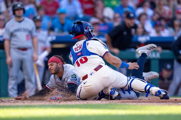 Minnesota Twins' Austin Martin, left, slides safely into home before Philadelphia Phillies catcher Rafael Marchan, right, can apply a tag during the sixth inning of a baseball game, Sunday, Sept. 28, 2025, in Philadelphia. (AP Photo/Chris Szagola)