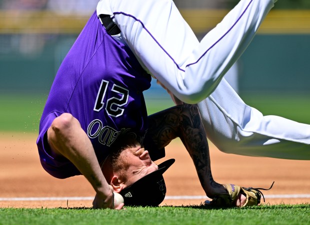 Colorado Rockies starting pitcher Kyle Freeland (21) rolls over trying to cover first base on a toss from first baseman Michael Toglia (4) on a reach by Detroit Tigers left fielder Zach McKinstry (39) in the first inning at Coors Field in Denver on Thursday, May 08, 2025. (Photo by Andy Cross/The Denver Post)