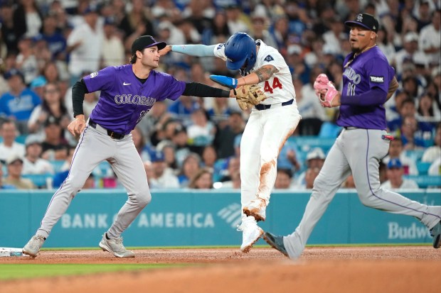 Los Angeles Dodgers' Andy Pages, center, is tagged out by Colorado Rockies third baseman Kyle Karros, left, as second baseman Orlando Arcia backs him up after Pages was caught between second and third on a fielders choice by Ben Rortvedt during the fourth inning of a baseball game Wednesday, Sept. 10, 2025, in Los Angeles. (AP Photo/Mark J. Terrill)