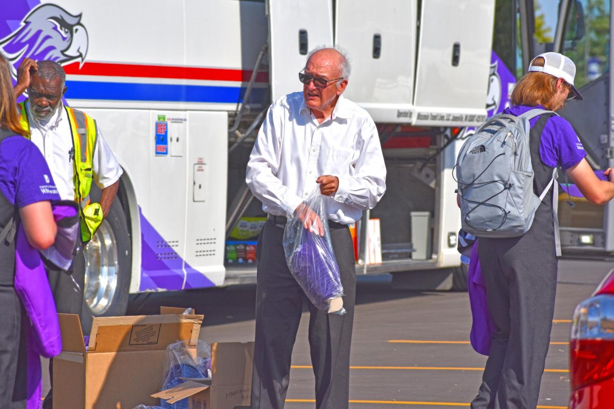 UW-Whitewater Band Director Dr. Glenn Hayes hands out hats to the UW-Whitewater Marching Band as they prepare to leave for the Milwaukee behind the Williams Center on September 27th, 2025.