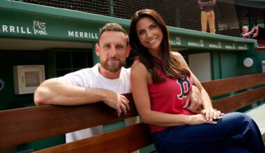 The couple poses in a dugout at Fenway. Jenny Dell is on the right sitting on a bench and wearing a red Boston Red Sox T-shirt. Will Middlebrooks is standing behind the bench on the left with his right arm around her.