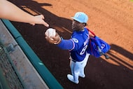 Texas Rangers infielder Sebastian Walcott  hands a ball back to a fan as he signs autographs...