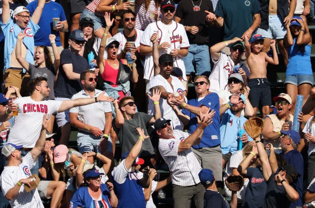 Fans reach for a solo home run ball hit by Cubs left fielder Ian Happ in the fourth inning against the Braves at Wrigley Field on Sept. 1, 2025, in Chicago. (John J. Kim/Chicago Tribune)