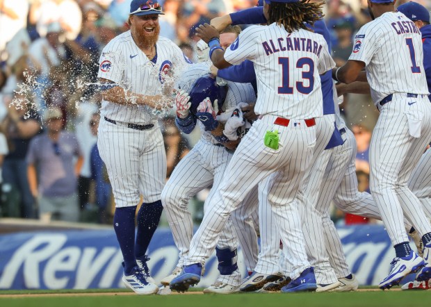 Cubs catcher Carson Kelly ducks for cover while getting mobbed by teammates after hitting a game-winning RBI single in the tenth inning against the Braves at Wrigley Field on Sept. 1, 2025, in Chicago. (John J. Kim/Chicago Tribune)