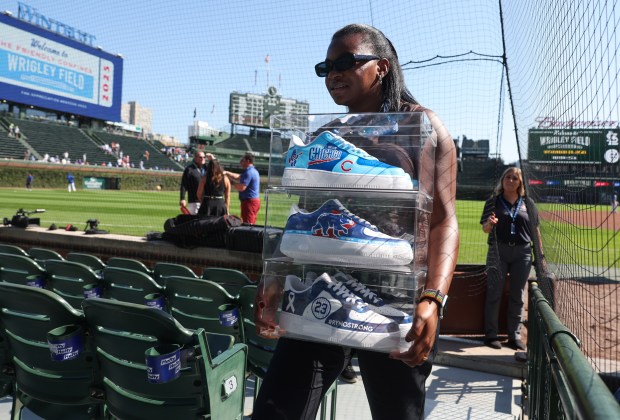 An employee carries a set of custom-designed shoes for Cubs Charities before a Cubs-Cardinals game at Wrigley Field on Sept. 27, 2025, in Chicago. (John J. Kim/Chicago Tribune)