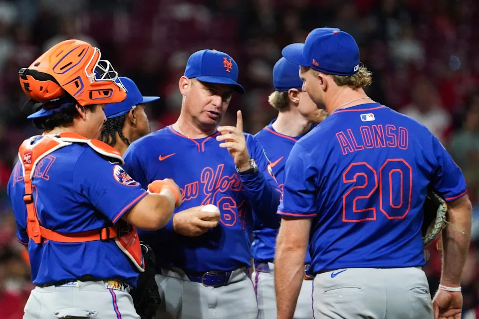 New York Mets manager Carlos Mendoza (64) speaks with players at the pitchers mound in the seventh inning of a MLB game between the Cincinnati Reds and New York Mets, Saturday, Sept. 6, 2025, at Great American Ball Park in downtown Cincinnati. Reds won 6-3.