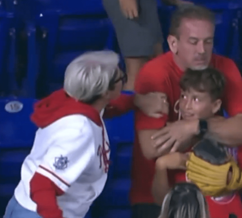 Woman taking a home run ball from a boy at a baseball game.