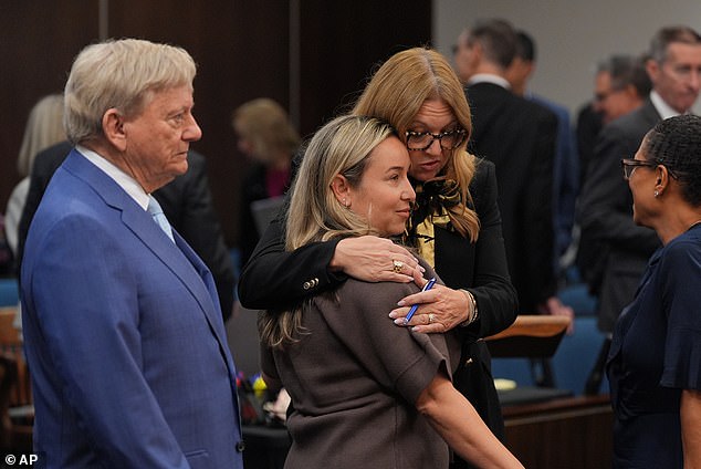 Skaggs' widow, Carli (center), is embraced at the trial for the wrongful death lawsuit