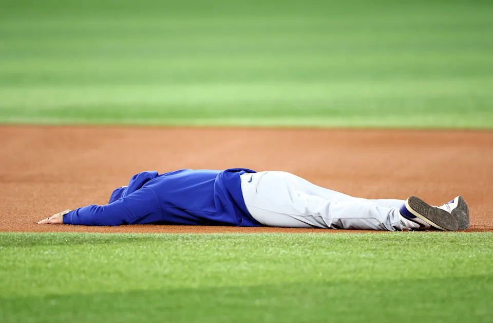 TORONTO, ON - OCTOBER 30:  Manager Dave Roberts of the Los Angeles Dodgers lays on the ground between second and third base after falling while having a running race with Hyeseong Kim #6 during a workout day ahead of game six of the 2025 World Series at Rogers Centre on October 30, 2025 in Toronto, Ontario, Canada.  (Photo by Vaughn Ridley/Getty Images)