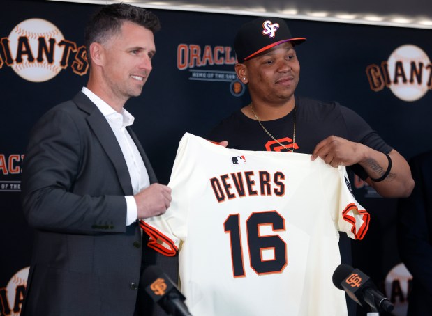 San Francisco Giants President of Baseball Operations Buster Posey, left, and San Francisco Giants' Rafael Devers (16) hold his jersey up as Devers is introduced before their game against the Cleveland Guardians at Oracle Park in San Francisco, Calif., on Tuesday, June 17, 2025. (Nhat V. Meyer/Bay Area News Group)