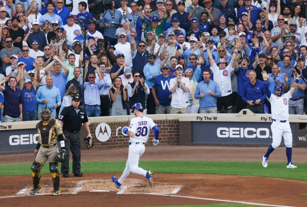 Dansby Swanson, right, and fans cheer as Kyle Tucker scores...