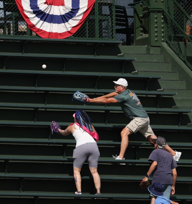 Fans try to catch a ball in the left field...