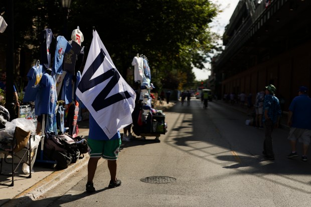 A fan with a "W" flag walks outside of Wrigley...