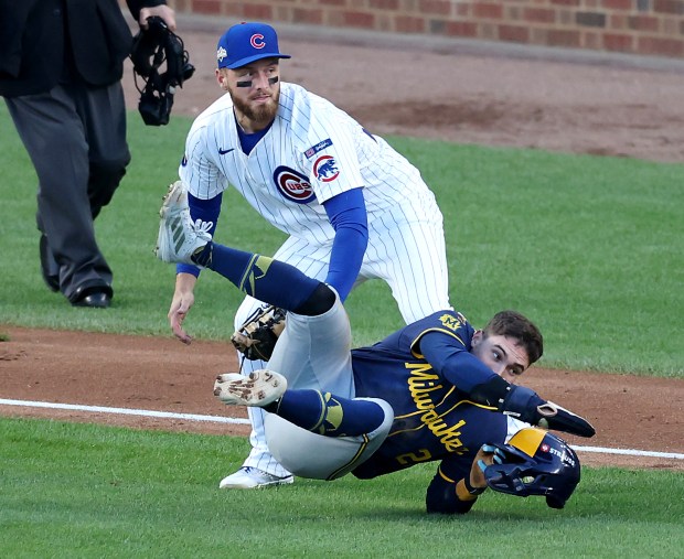 Cubs first baseman Michael Busch tags out Brewers baserunner Caleb...