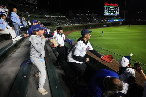 Fans try to catch a ball in the left field...