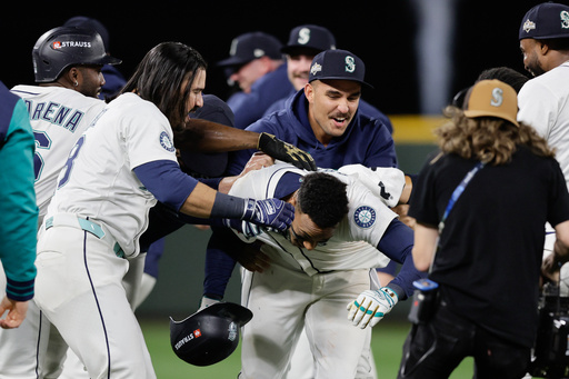 Seattle Mariners players celebrate with Jorge Polanco, center, after he hit the game-winning RBI single in the 15th inning in Game 5 of baseball