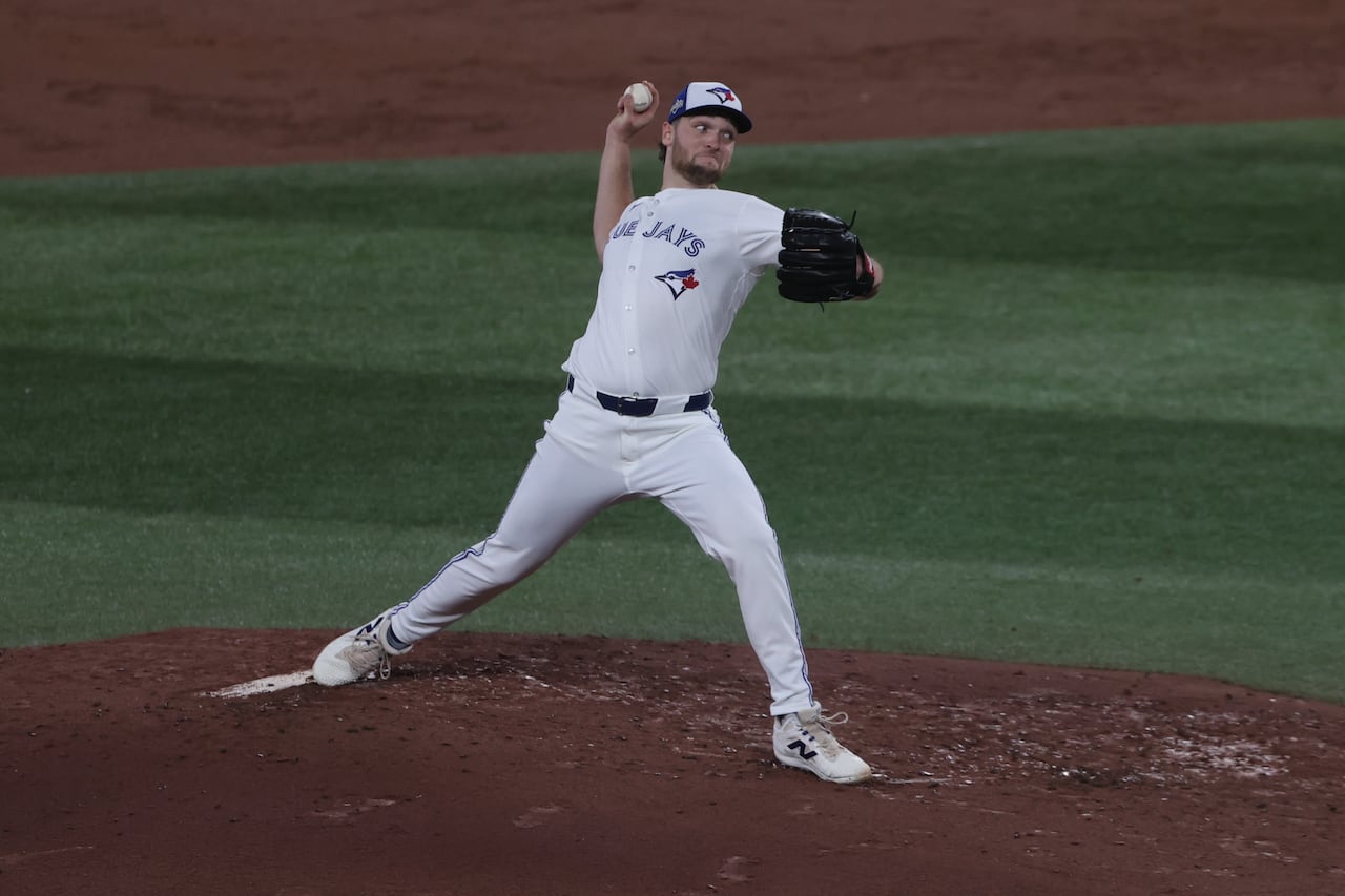 A player in white pulls his arm back to pitch. 