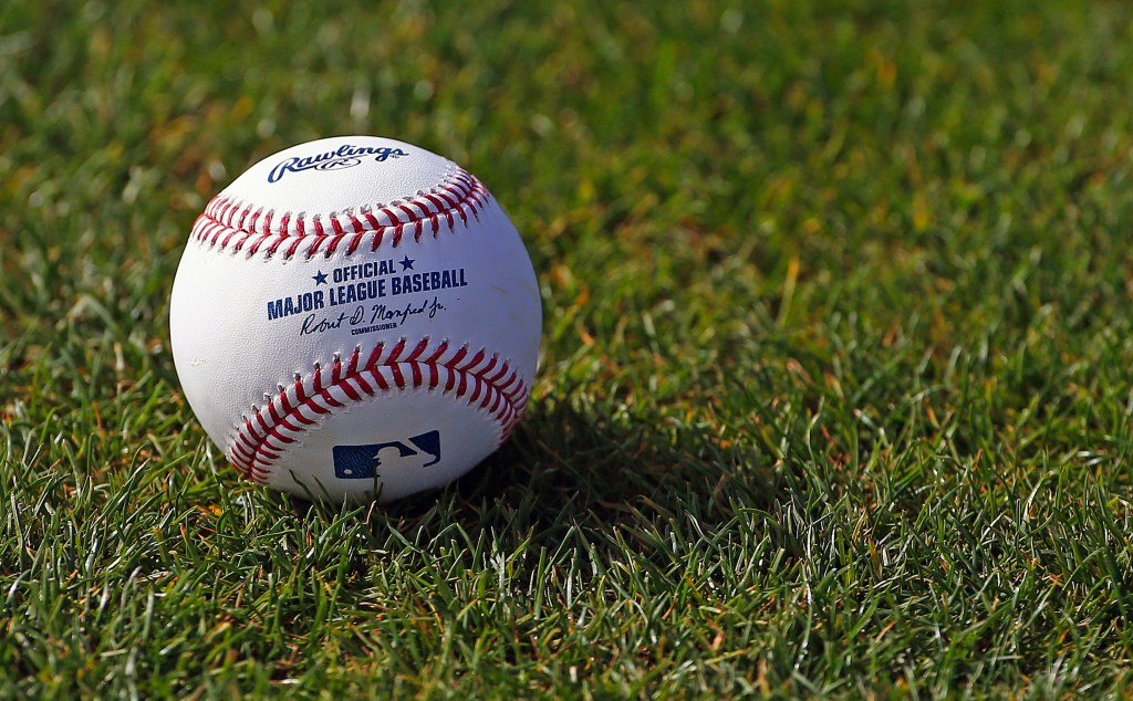 A Major League Baseball ball sits in green grass.
