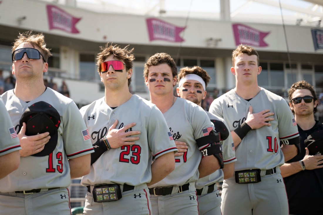 Baseball players stand with hands over their hearts during the national anthem.