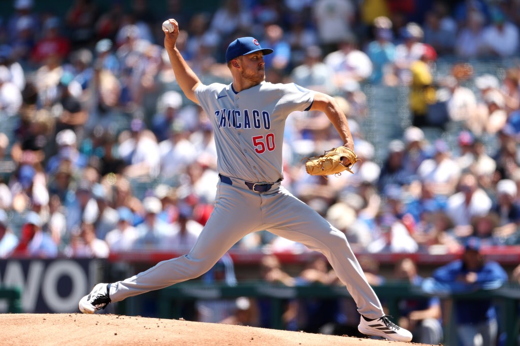 A Chicago Cubs pitcher in a grey uniform mid-delivery.