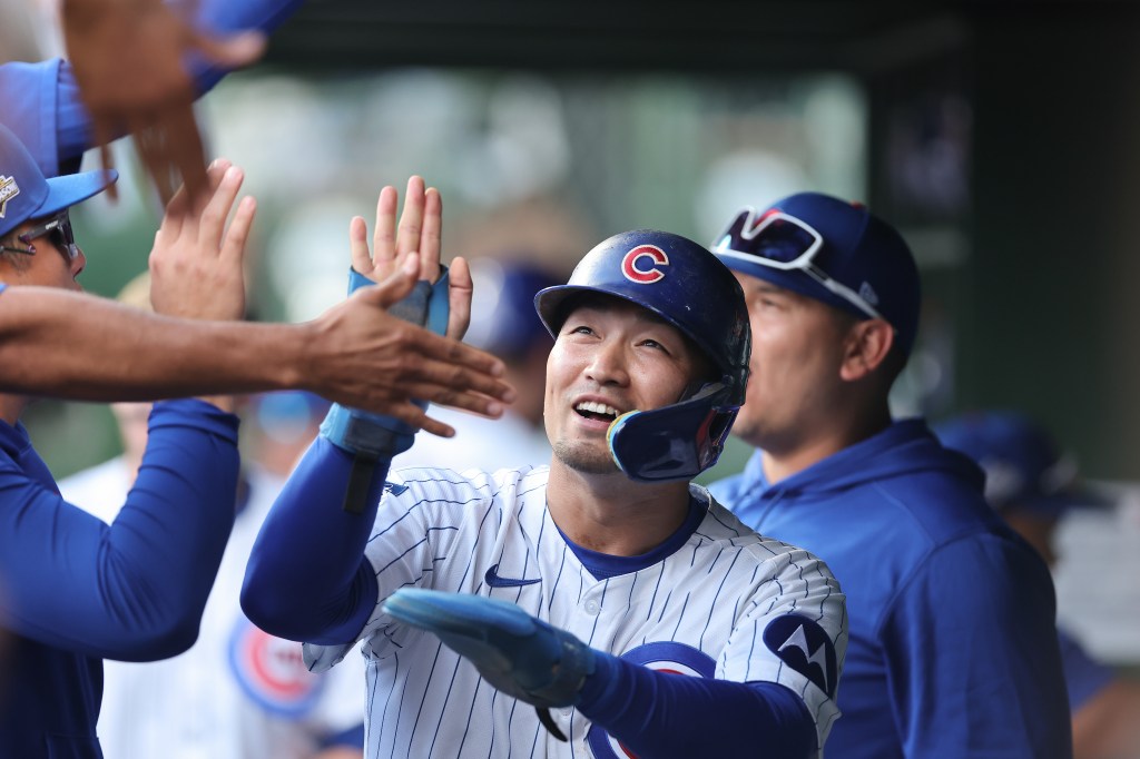 Seiya Suzuki high-fiving teammates in the dugout after scoring a run.