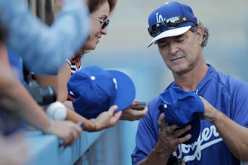 Dodgers manager Don Mattingly signs autographs before a game against the San Diego Padres.