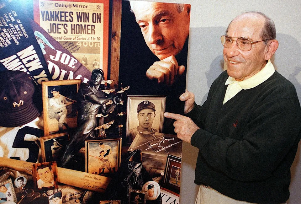 Former New York Yankees catcher Yogi Berra holds a montage of photos of Yankees legend Joe DiMaggio.
