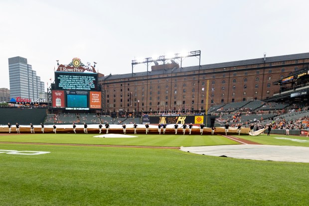 The grounds crew rolls out the tarp on the field...