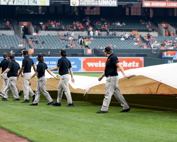 The grounds crew rolls out the tarp on the field...