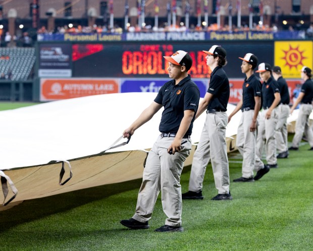The grounds crew rolls out the tarp on the field...