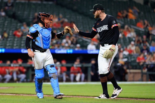 Baltimore Orioles relief pitcher Bryan Baker, right, high-fives catcher Maverick...