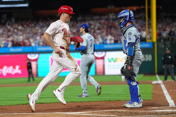 The Philadelphia Phillies’ J.T. Realmuto scores past Dodgers catcher Ben...