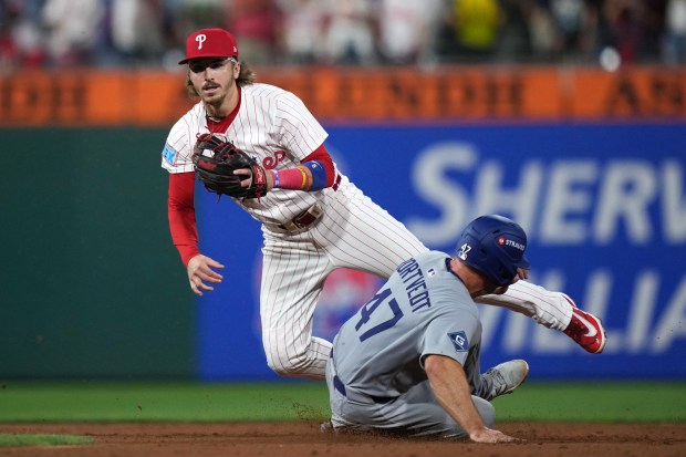 Philadelphia Phillies second baseman Bryson Stott, left, falls after forcing...