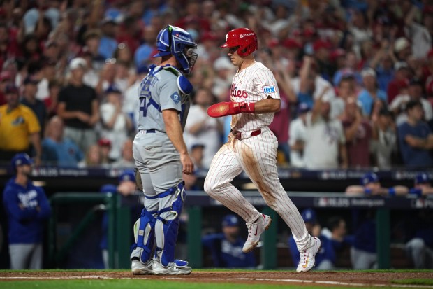 The Philadelphia Phillies’ J.T. Realmuto, right, scores past Dodgers catcher...