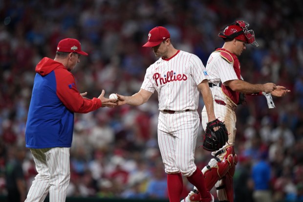 Philadelphia Phillies relief pitcher David Robertson, center, is pulled by...
