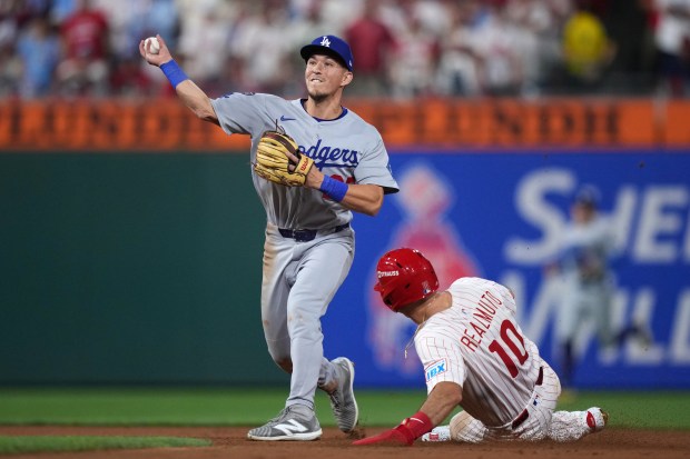 Los Angeles Dodgers second baseman Tommy Edman, left, throws to...