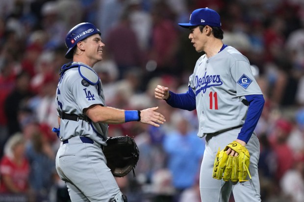 Dodgers catcher Will Smith, left, and relief pitcher Roki Sasaki...