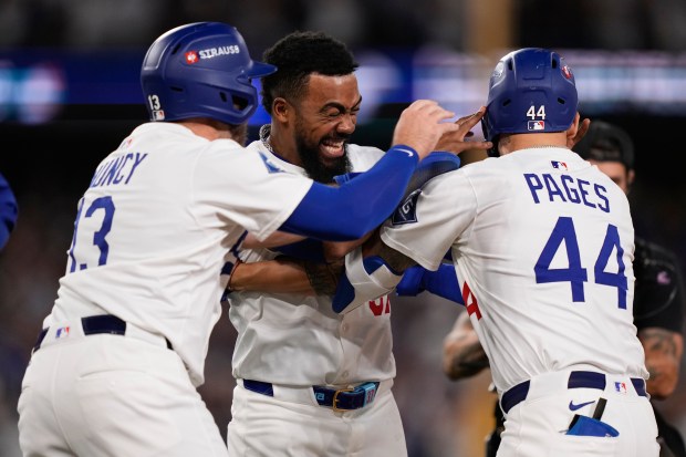 The Dodgers’ Andy Pages (44) is hugged by teammates Teoscar...