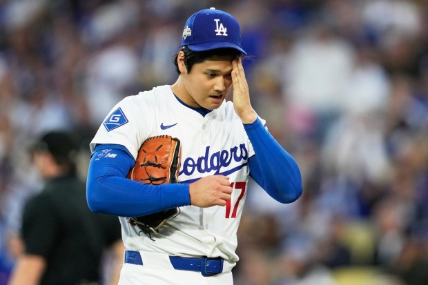 Dodgers starting pitcher Shohei Ohtani wipes his face during the...
