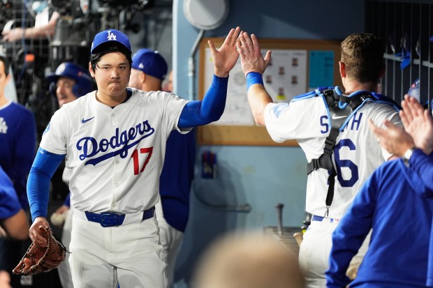 Dodgers starting pitcher Shohei Ohtani celebrates in the dugout after...