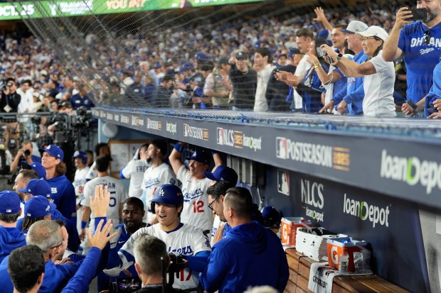Dodgers star Shohei Ohtani (17) celebrates in the dugout as...