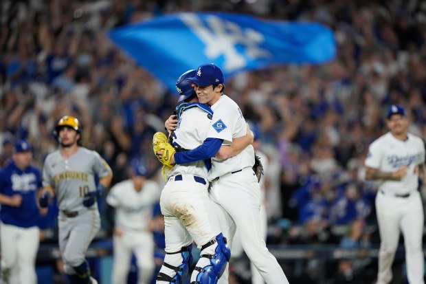 Dodgers relief pitcher Roki Sasaki and catcher Will Smith embrace...