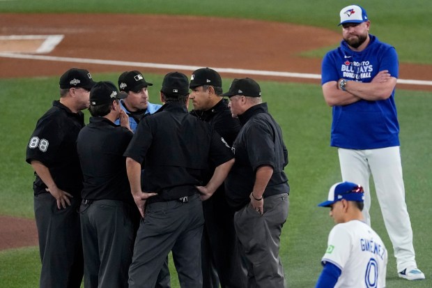 Toronto Blue Jays manager John Schneider, right, stands back as the umpires confer on a call during the first inning in Game 7 of baseball's American League Championship Series against the Seattle Mariners, Monday, Oct. 20, 2025, in Toronto. (AP Photo/David J. Phillip)