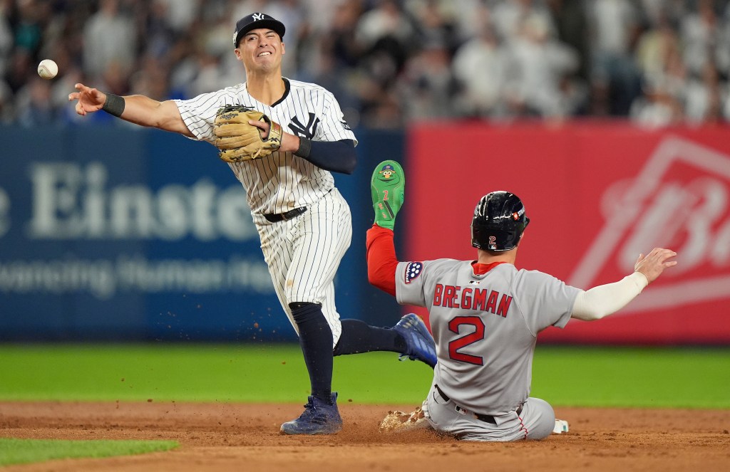 Anthony Volpe makes a throw to first for a double play as Boston Red Sox Alex Bregman slides during the eighth inning of the Yankees' 4-3 win over the Red Sox in Game 2 of their AL wild-card series.