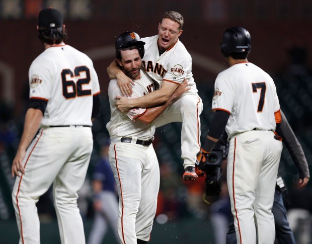 San Francisco Giants' Nick Hundley (5) congratulates San Francisco Giants' Madison Bumgarner (40) on his walk-off single which scored San Francisco Giants' Gorkys Hernandez (7) against the San Diego Padres to win the game 5-4 in the 12th inning at AT&T Park in San Francisco, Calif., on Tuesday, September 25, 2018. (Nhat V. Meyer/Bay Area News Group)