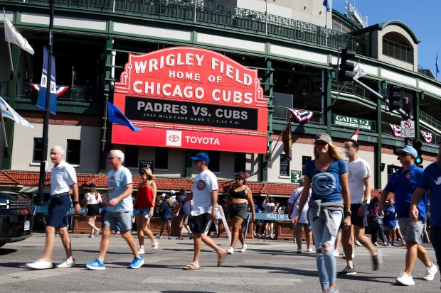 People walk in front of the marquee outside of Wrigley...