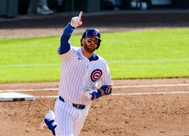 Chicago Cubs catcher Carson Kelly points toward his home run...