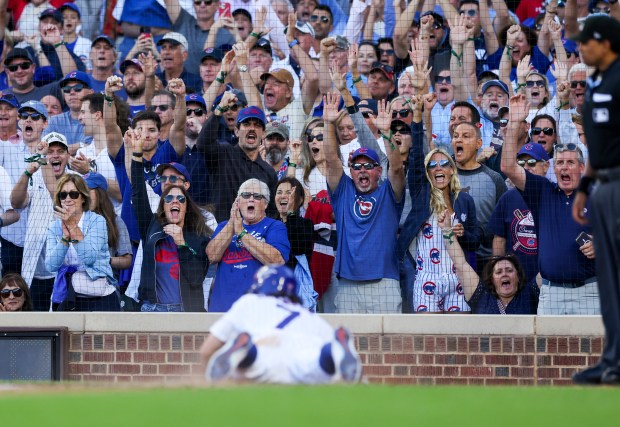 Cubs fans celebrate after shortstop Dansby Swanson scores on sacrifice...