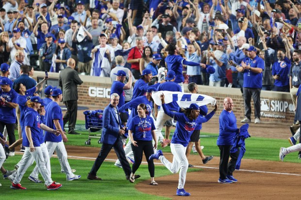 Chicago Cubs players and fans celebrate after the Cubs won...